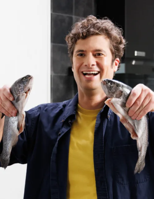 A comedian holding two fish, grinning